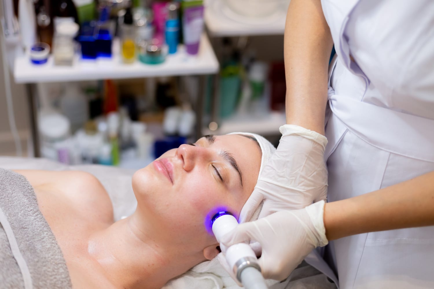 A woman receiving a facial treatment with a device at a spa.
